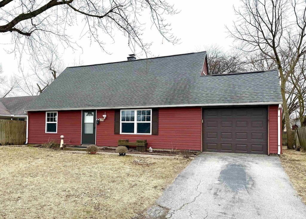 view of front facade with aphalt driveway, a garage, fence, roof with shingles, and a chimney