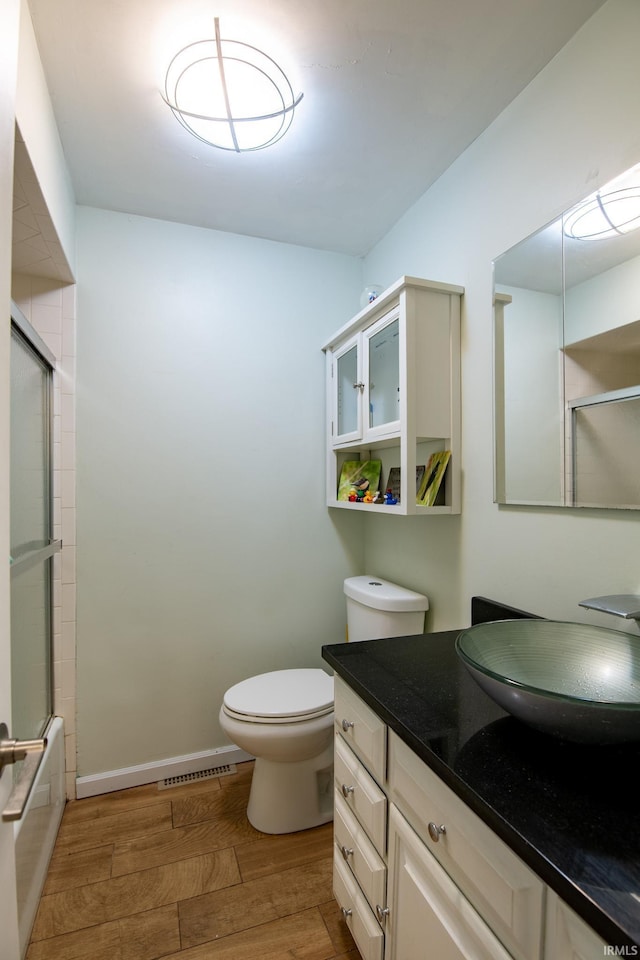 full bathroom featuring baseboards, visible vents, a baseboard radiator, wood finished floors, and vanity