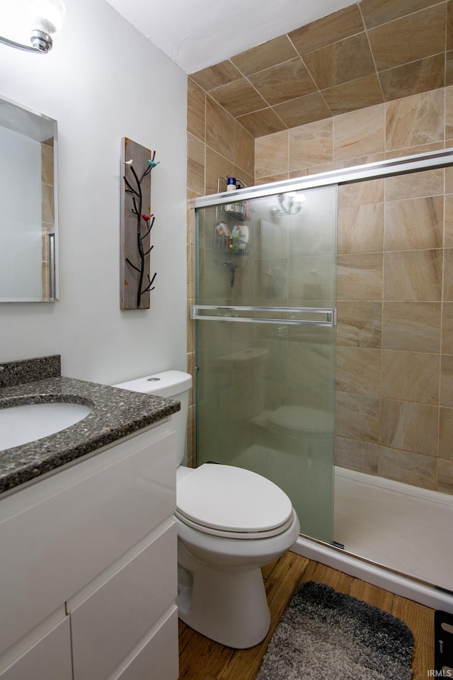 full bathroom featuring toilet, a shower stall, vanity, and wood finished floors