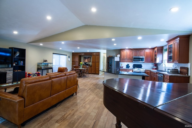 living room with light wood-style floors, recessed lighting, vaulted ceiling, and a stone fireplace