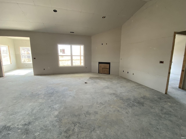 unfurnished living room featuring a healthy amount of sunlight, unfinished concrete floors, and a fireplace