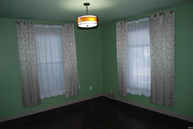 spare room featuring visible vents, baseboards, and wood finished floors