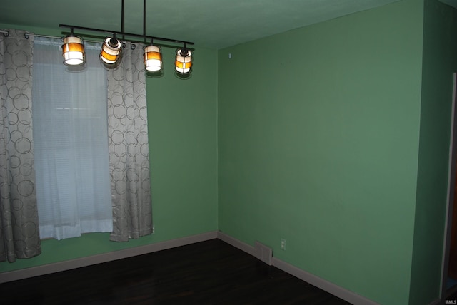 spare room with baseboards and dark wood-type flooring