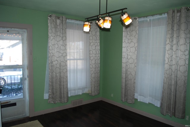 unfurnished room with dark wood-style flooring, visible vents, plenty of natural light, and baseboards