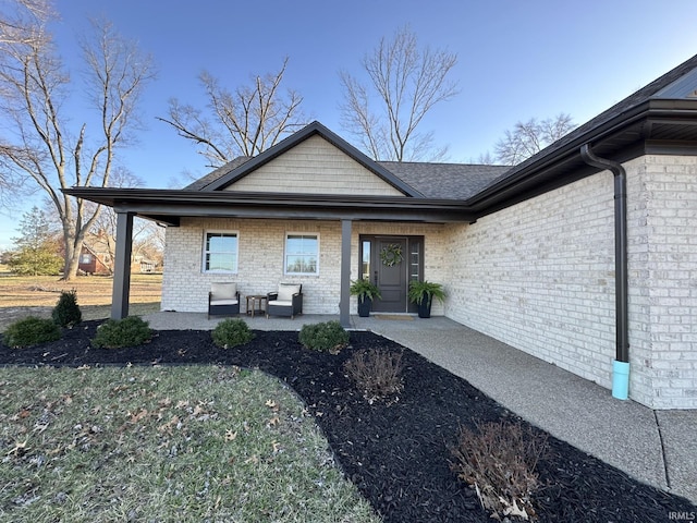 entrance to property with brick siding and a porch