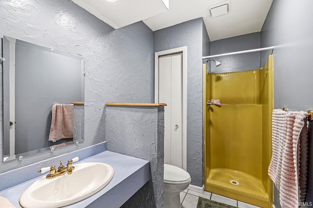 bathroom with a textured wall, a shower stall, toilet, and tile patterned floors