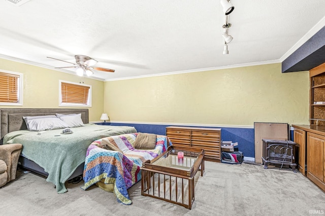 carpeted bedroom with a textured ceiling, ornamental molding, track lighting, and a textured wall