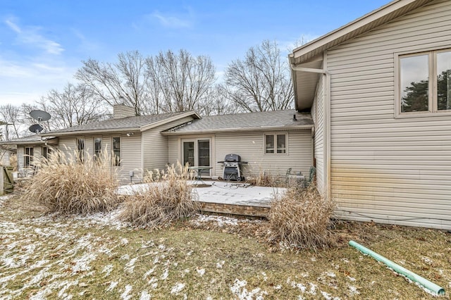 rear view of property featuring a chimney and a deck