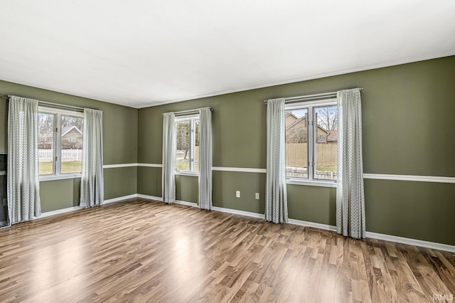 spare room with baseboards and wood finished floors