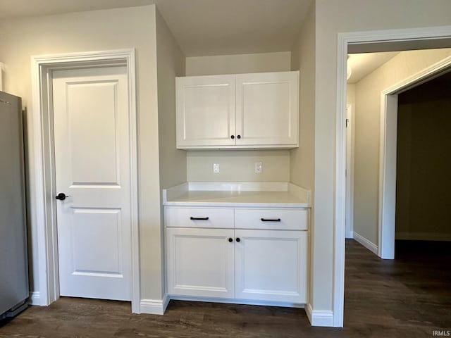 kitchen with dark wood-style floors, freestanding refrigerator, light countertops, and white cabinetry