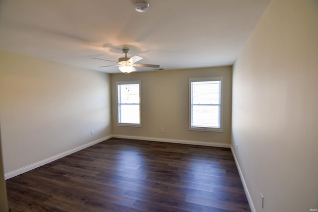 unfurnished room with dark wood-type flooring, a wealth of natural light, ceiling fan, and baseboards