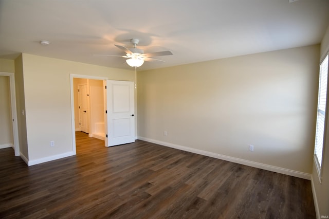 spare room featuring a ceiling fan, dark wood finished floors, and baseboards