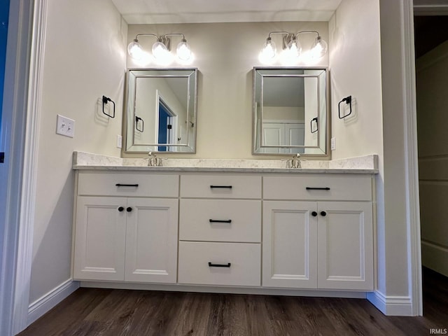 full bathroom featuring double vanity, baseboards, and wood finished floors