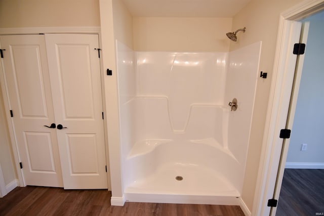 bathroom with a shower, baseboards, and wood finished floors