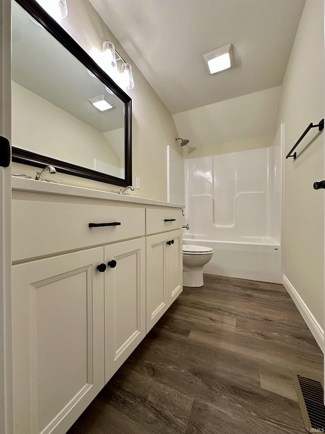 bathroom with toilet, lofted ceiling, shower / tub combination, wood finished floors, and vanity