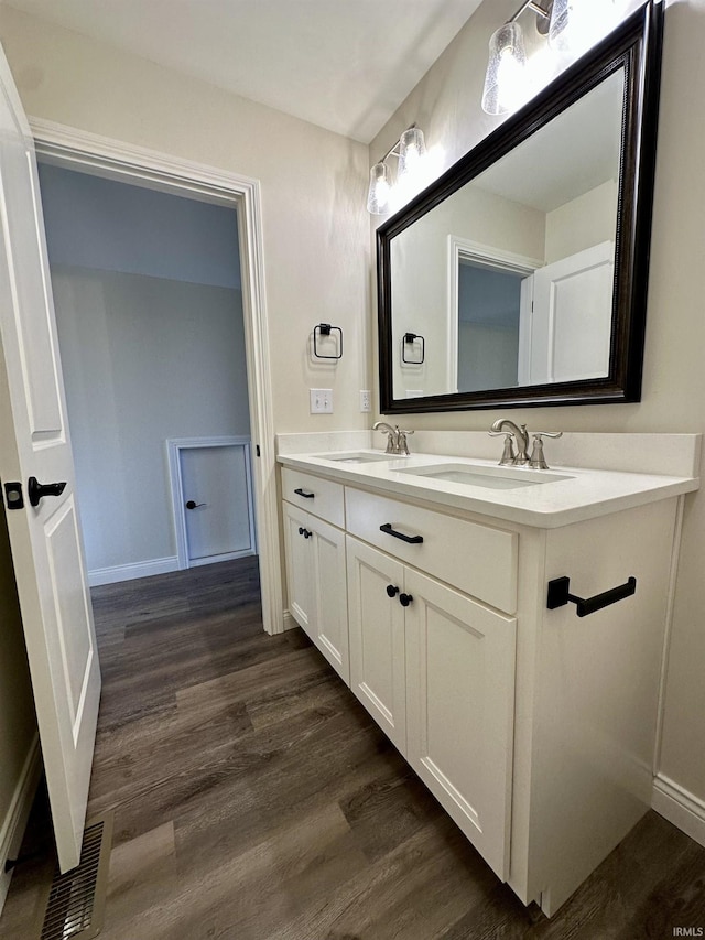 bathroom featuring double vanity, a sink, visible vents, and wood finished floors