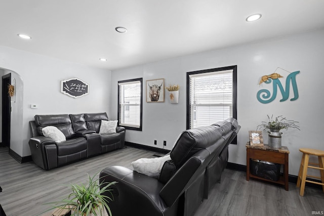 living room with light wood-type flooring, baseboards, arched walkways, and recessed lighting