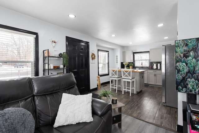 living area with baseboards, dark wood-type flooring, and recessed lighting