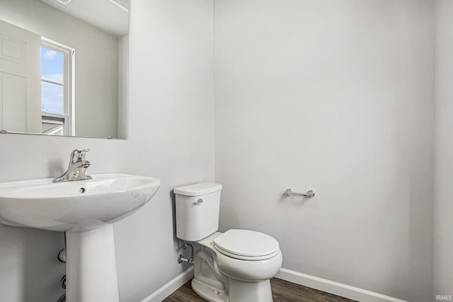 bathroom with toilet, baseboards, and wood finished floors