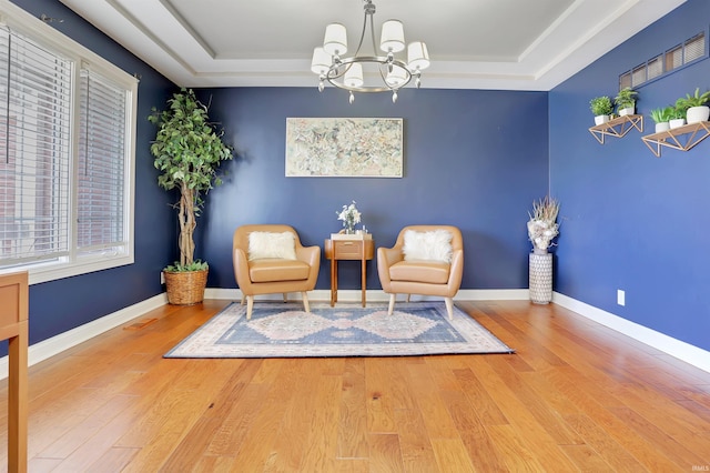 sitting room with a tray ceiling, baseboards, and wood finished floors