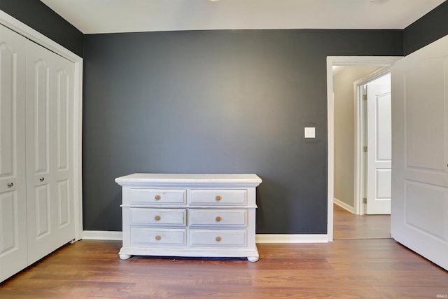 unfurnished bedroom featuring a closet, wood finished floors, and baseboards