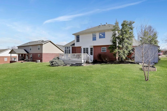 back of house with brick siding, a lawn, and a deck