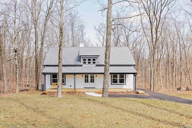 modern farmhouse featuring a porch, a front yard, roof with shingles, and a chimney