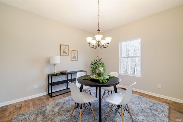 dining room with a chandelier, wood finished floors, and baseboards