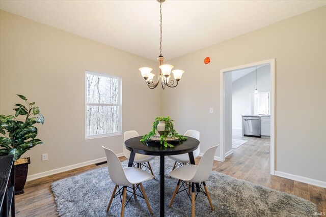 dining area featuring light wood-style flooring, baseboards, and an inviting chandelier