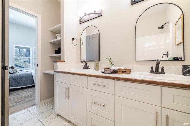 full bathroom featuring marble finish floor, double vanity, walk in shower, and a sink