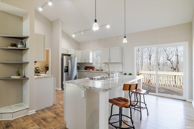 kitchen with light wood-type flooring, light countertops, a sink, and stainless steel fridge with ice dispenser