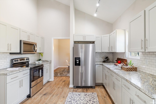 kitchen with stainless steel appliances, light wood-style floors, and light stone counters