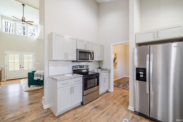 kitchen featuring appliances with stainless steel finishes, french doors, a healthy amount of sunlight, and a high ceiling