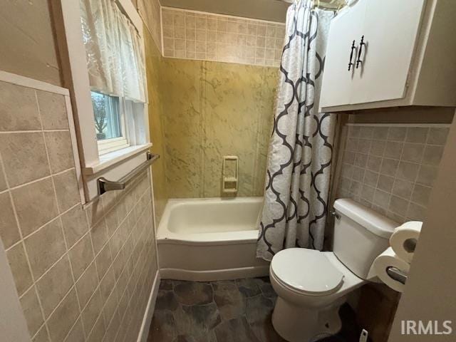 bathroom with toilet, shower / bath combo, and tile walls