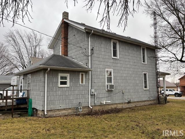 view of property exterior featuring a yard, a chimney, and cooling unit