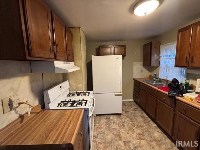 kitchen with white appliances, a sink, and butcher block counters