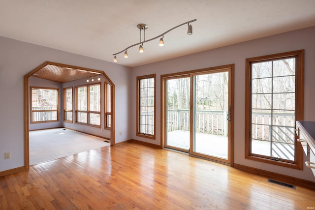 interior space with a wealth of natural light, visible vents, baseboards, and light wood-style floors