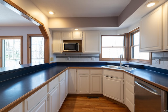 kitchen featuring white cabinetry, dark countertops, appliances with stainless steel finishes, and a sink