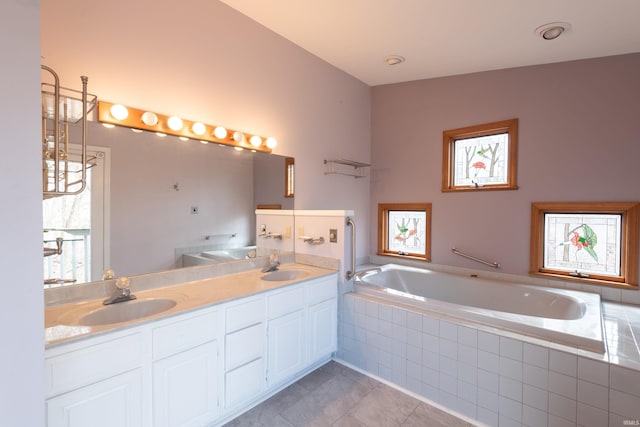 bathroom with double vanity, a bath, tile patterned floors, and a sink