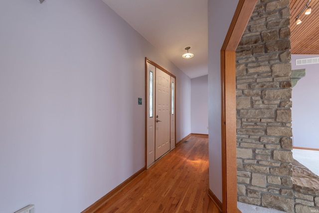 corridor featuring wood finished floors, baseboards, and visible vents