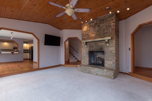 unfurnished living room featuring a stone fireplace, wood ceiling, carpet floors, and vaulted ceiling