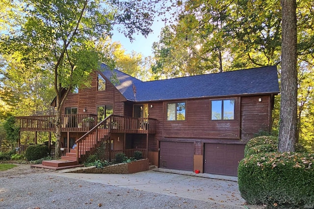 view of front of property featuring a shingled roof, stairway, an attached garage, a deck, and driveway