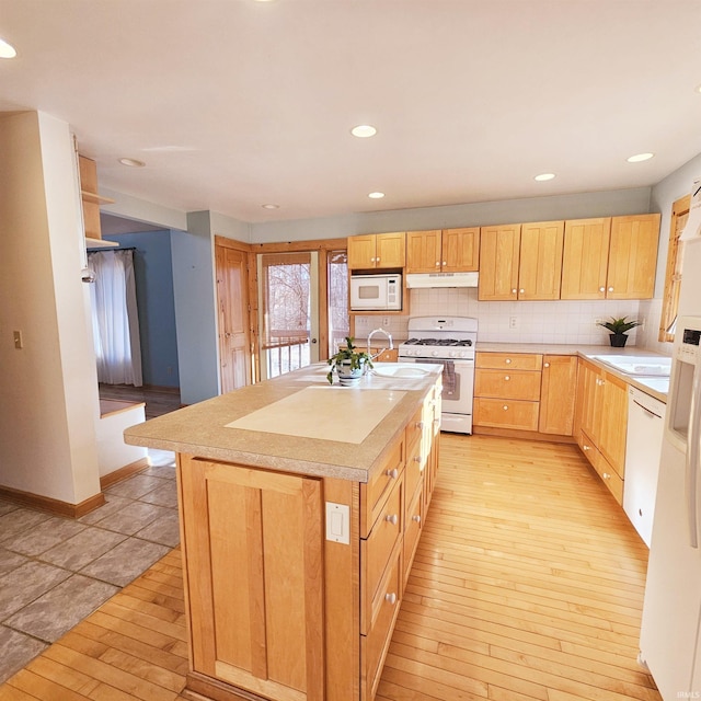 kitchen featuring light countertops, light wood-style flooring, backsplash, light brown cabinets, and white appliances