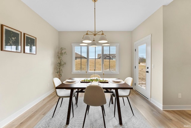 dining space with light wood-type flooring and baseboards