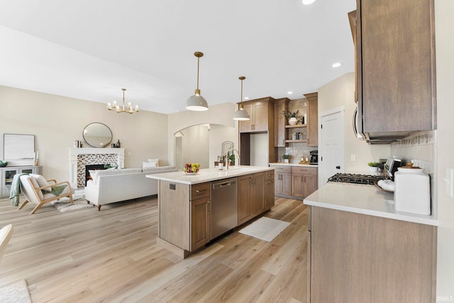 kitchen featuring tasteful backsplash, light countertops, a tiled fireplace, stainless steel dishwasher, and range