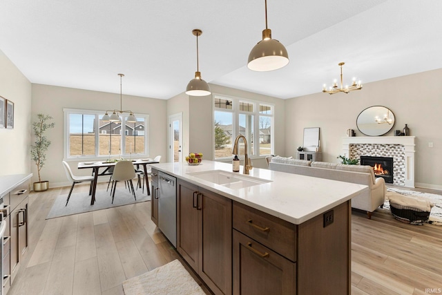 kitchen featuring light wood-style floors, a notable chandelier, a sink, and stainless steel dishwasher