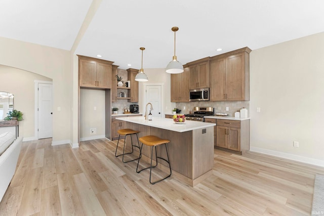 kitchen featuring stainless steel microwave, range, backsplash, and a kitchen breakfast bar