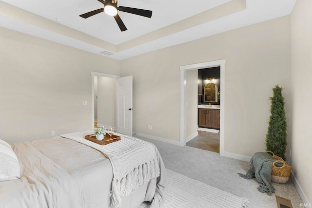 carpeted bedroom featuring a raised ceiling, visible vents, and baseboards