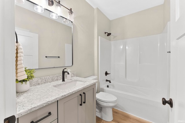 full bath featuring vanity, bathing tub / shower combination, wood finished floors, and toilet