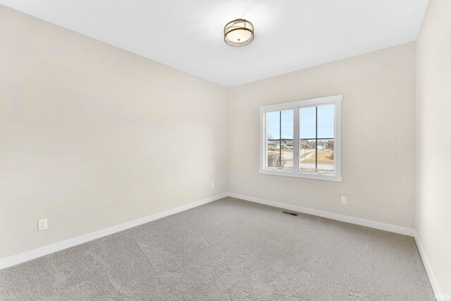 carpeted spare room featuring visible vents and baseboards